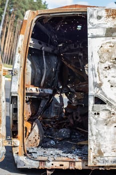 Cars after the fire. Iron parts of a burnt car. Burnt-out cars abandoned on the side of a quiet countryside. Explosion, the result of a fire. Car insurance concept. War of Russia against Ukraine