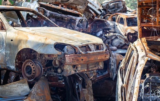 The car burned down completely, even the tires burned out. Burnt out car crash after fire. The bomb shell of the terrorist attack blew up civilians. Disaster zone. Abandoned car on the road