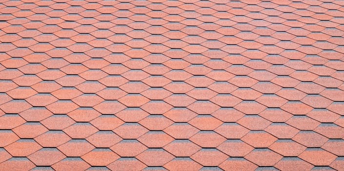 New roof with red shingles. Tiles on the roof of the house. Use to advertise roof fabrication and maintenance. Spotted texture. Affordable roofing. High quality photo with copy space