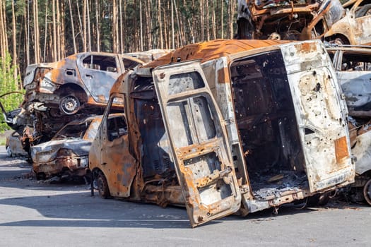 Cars after the fire. Iron parts of a burnt car. Burnt-out cars abandoned on the side of a quiet countryside. Explosion, the result of a fire. Car insurance concept. War of Russia against Ukraine