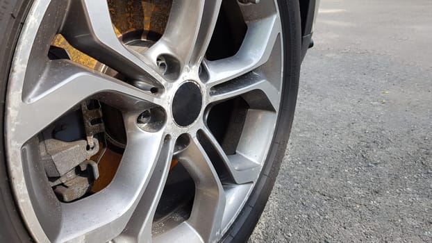 The original alloy wheel, dirty and scratched on the car close-up. Worn car wheels are waiting for repair. selective focus. Car repair and restoration concept required. Damaged car wheel