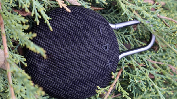 Waterproof round black Bluetooth speaker with carabiner. Digital music and audio concept. Mini, suitable for travel