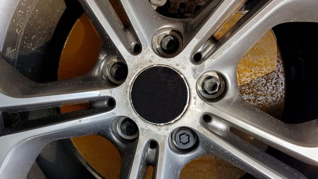 The original alloy wheel, dirty and scratched on the car close-up. Worn car wheels are waiting for repair. selective focus. Car repair and restoration concept required. Damaged car wheel