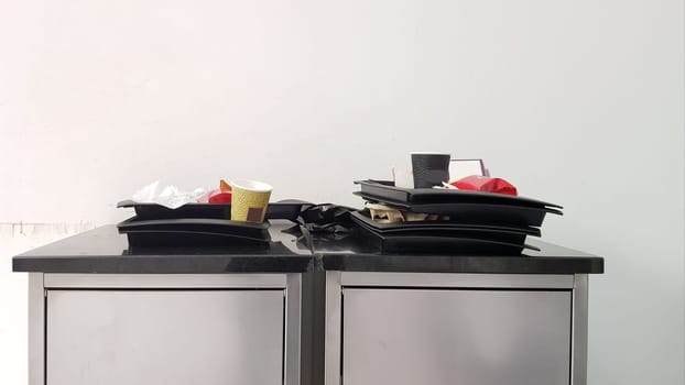 The concept of cleanliness and cleaning rules. At the exit of the fast food trash can with trays. Cleanliness and care for the environment. Tin trash can in cafes and self-service restaurants