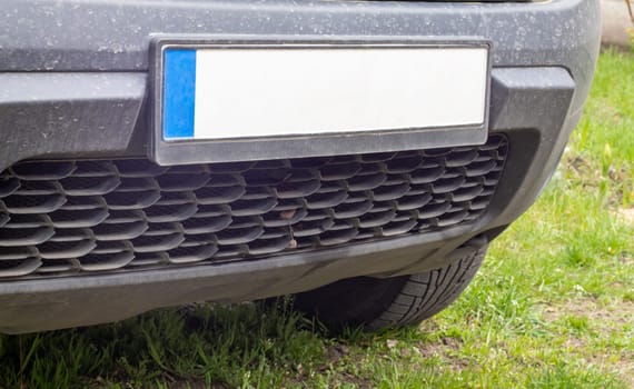 Car number without letters and numbers on the car bumper. Blank white license plate in front of the car, all logos removed, close up. The front rectangular license plate of a vehicle on the street