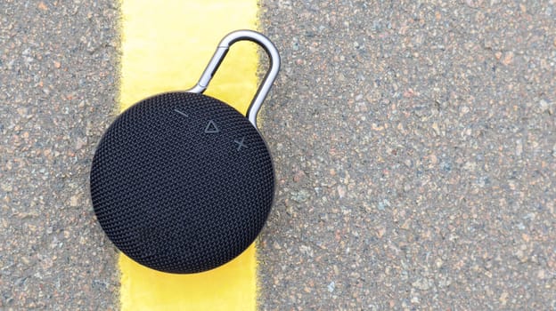 Waterproof round black Bluetooth speaker with carabiner. Digital music and audio concept. Mini, suitable for travel