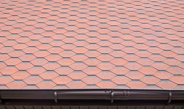 New roof with red shingles. Tiles on the roof of the house. Use to advertise roof fabrication and maintenance. Spotted texture. Affordable roofing. High quality photo with copy space