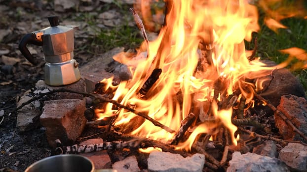 Bonfire burning in tourist camp in mountains. Beautiful campfire, burning wood in summer evening. Active lifestyle, traveling, hiking and camping concept. Campfire burning in slow motion.