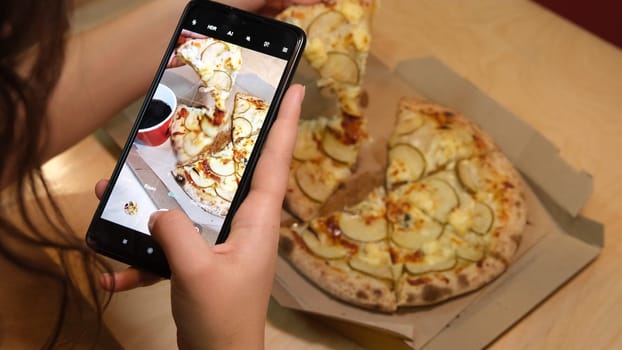 woman hand with smartphone photographing pizza at restaurant or cafe. Vegetarian pizza, vegetarian food, woman shoot vegetarian pizza