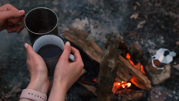 Couple in love Campsite With Fire Pit and Two Tin Cups with hot tea, coffee. Burning Campfire.