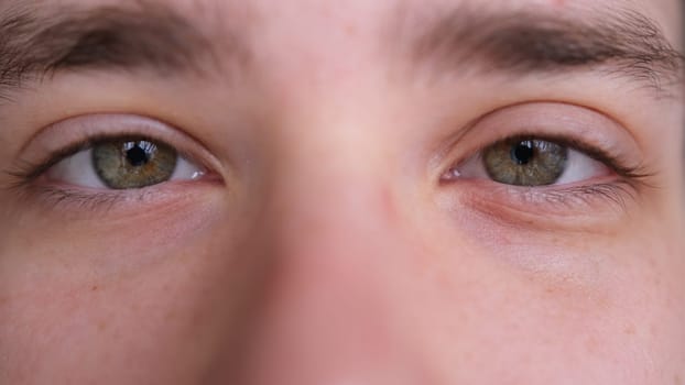 Close up of Man's face. Attractive boy with his beautiful green eyes. European young male model looking at camera.extreme close-up, 4K.