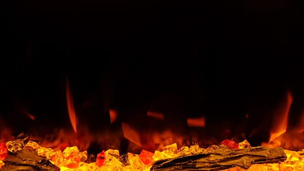 view on electric fireplace with artificial sparkling flame, decor for the interior, orange flame on crystals.
