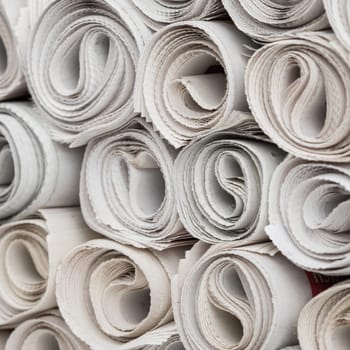 Stack of newspapers rolls, paper texture background.