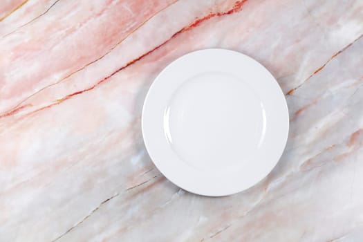 A dinner plate on a pink white and grey marble surface