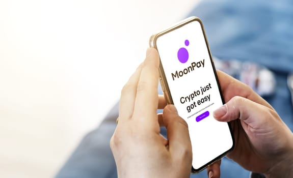 London, UK, May 2022: Woman holding a phone with Moonpay mobile application on screen. MoonPay is a financial technology company that builds payments infrastructure for crypto