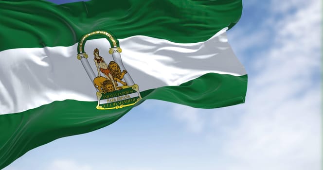 Andalusian flag waving in the wind on a clear day. Andalusia is the southernmost autonomous community in Peninsular Spain, the most populous and the second largest autonomous community in the country