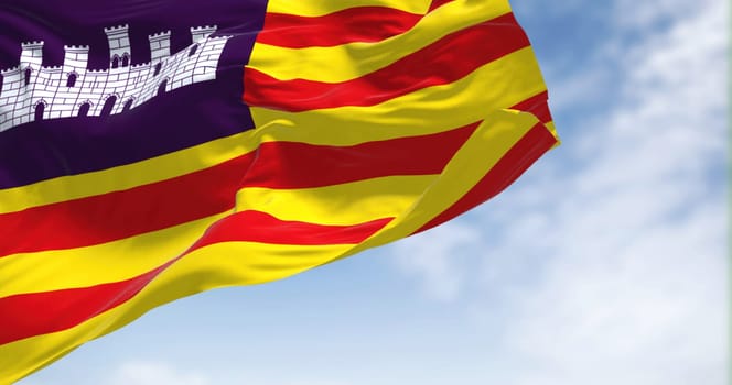 Balearic Islands flag waving in the wind on a clear day. The Balearic Islands are a Spanish archipelago in the Balearic Sea, near the eastern coast of the Iberian Peninsula