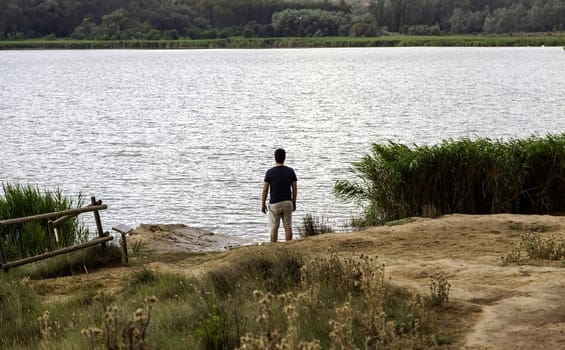 Detail of young man contemplating a lake, relaxation and tranquility