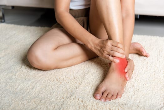 Foot pain, Woman holds her ankle injury feeling pain in her foot at home, female suffering from feet ache use hand massage relax muscle from ankle in home interior, Healthcare problems and medical