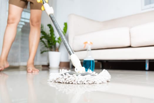 Asian woman washes the floor with a mop and rag indoors, housewife washing floor mopping at home in living room cleaning her home, Professional housekeeping job house cleanup concept