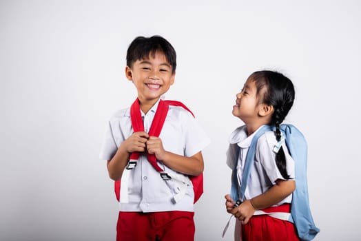 Two Asian student kid girl boy schoolchildren brother sister smile happy wear student thai uniform red pants skirt in studio shot isolated on white background, Portrait little children girl preschool