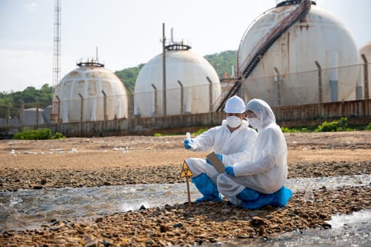 Ecologist sampling taken dead fish to inspaction and save data to laptop computer, Biologist wear protective suit and mask collects sample of waste water from industry, problem environment