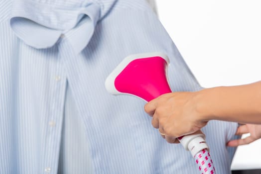 Close up of woman using electric hand steam generator while it is hot and steam comes out for clothes shirt at house, Household & home equipment for housework, concept of linen care