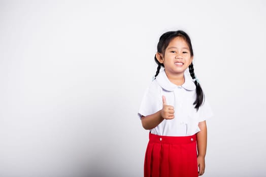 Asian adorable toddler smiling happy wear student thai uniform red skirt show thumb up finger in studio shot isolated on white background, Portrait little children girl preschool, Kid Back to school