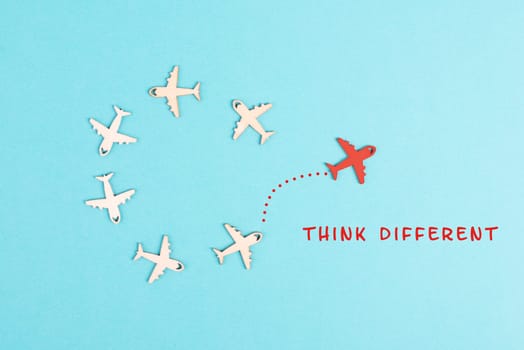 Group of airplanes flying in a circle, red plane thinks different and takes the opposite direction, against the stream symbolic, courage and winner concept