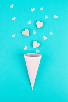 Cone with rose colored hearts, blue background, birthday and valentines day greeting card, spreading love, positive emotion, flat lay
