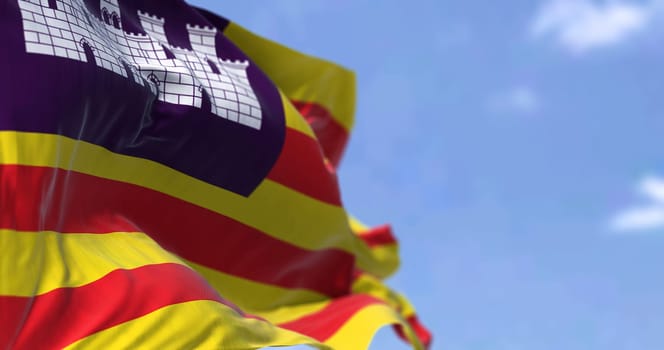 Rear view of the Balearic Islands flag waving in the wind on a clear day. The Balearic Islands are a Spanish archipelago in the Balearic Sea, near the eastern coast of the Iberian Peninsula