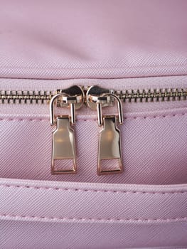 gold zippers with gold zippers are fastened on a pink leather object, close-up. High quality photo