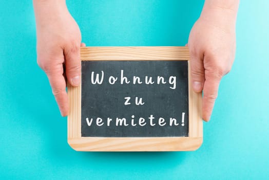 Holding a chalkboard in the hands, apartment for rent is standing in german language on the sign, moving to a new home, real estate