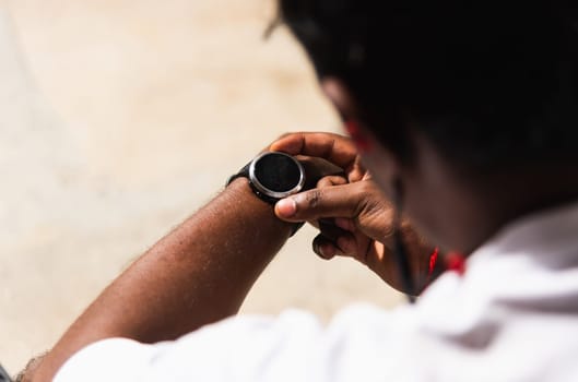 Close up Asian young athlete sport runner black man wear modern time smart watch he sitting resting before training running at the outdoor street health park, healthy exercise before workout concept