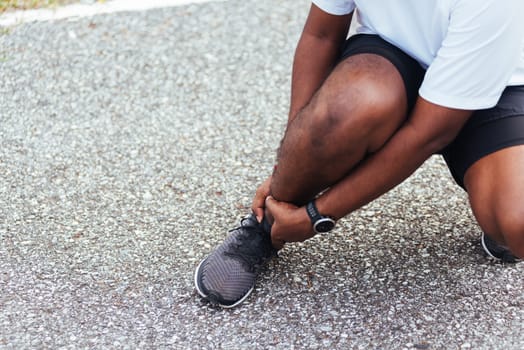 Close up Asian young sport runner black man wear watch hands joint hold leg pain because of twisted ankle broken while running at the outdoor street health park, healthy exercise Injury from workout