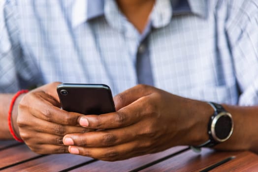 Happy Asian black businessman person holding a modern digital smart phone blank screen device technology and connecting networking online at the coffee cafe shop