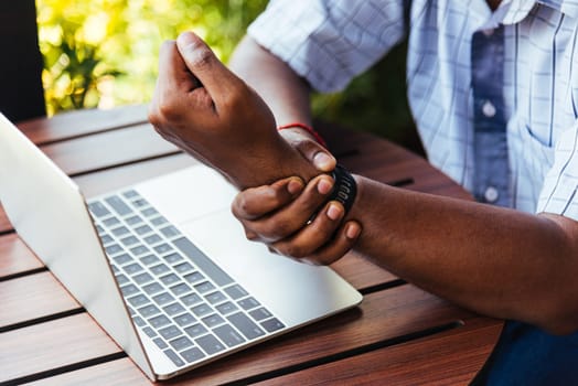 Closeup hands the Asian black man holding his wrist pain from using laptop computer he working long time, Injury office syndrome hand pain by occupational disease concept