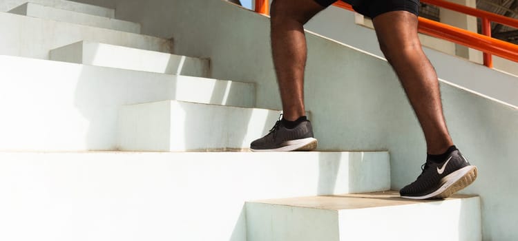 Close up athlete shoes of legs young sport runner black man step running up to climbing stairs doing training cardio sport workout at the outdoor street, healthy exercise before workout concept