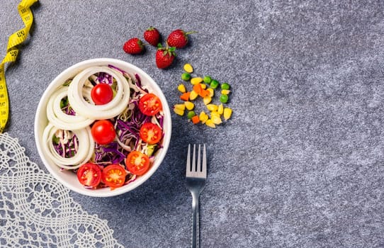 Top view of the healthy colorful salad bowl with tomatoes fresh mixed greens vegetable in a dish and measuring tape on cement background, Health salad snack diet food weight loss concept