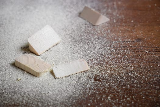 closeup of cut pieces of wood with sawdust on brown wooden floor