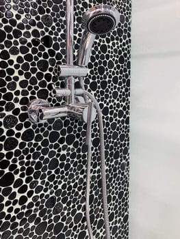 front view closeup of shower cabin with chrome head and faucet decorated with black pebbles