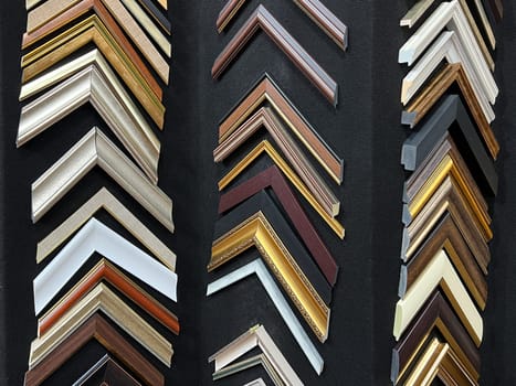 many picture and painting art wooden frame samples in different sizes and color exhibited on a black wall