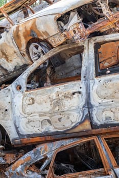 A view of burnt-out cars after rocket attacks by the Russian military. War of Russia against Ukraine. Civil vehicle after the fire. Cemetery of cars in the city of Irpin. Rusty pile of metal