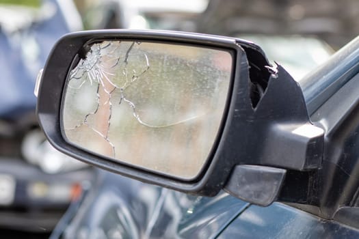Close up broken left side rearview mirror of a car in blue. Auto insurance concept. Broken side glass of the car on the driver's side as a result of an accident. Criminal incident