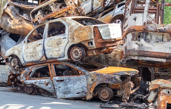 A view of burnt-out cars after rocket attacks by the Russian military. War of Russia against Ukraine. Civil vehicle after the fire. Cemetery of cars in the city of Irpin. Rusty pile of metal