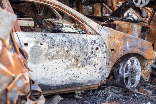 Burnt car body riddled with bullets. Russia's war against Ukraine. Shot by the Russian military car of civilians during the evacuation. Traces of bullets and fragments of shells