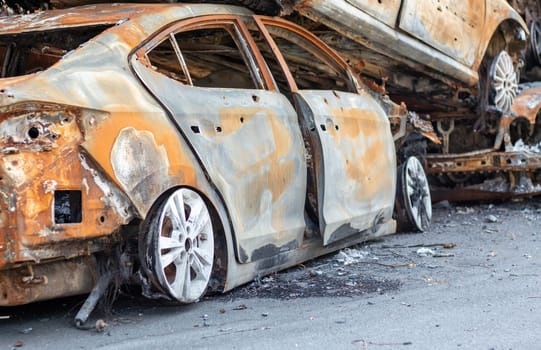 A view of burnt-out cars after rocket attacks by the Russian military. War of Russia against Ukraine. Civil vehicle after the fire. Cemetery of cars in the city of Irpin. Rusty pile of metal