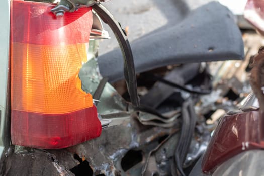 A red and orange broken glass lamp on a car as a result of a violent collision. Broken rear headlight close-up due to a car accident or careless driving. Insured event, safe driving concept