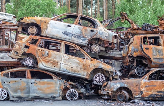 A view of burnt-out cars after rocket attacks by the Russian military. War of Russia against Ukraine. Civil vehicle after the fire. Cemetery of cars in the city of Irpin. Rusty pile of metal