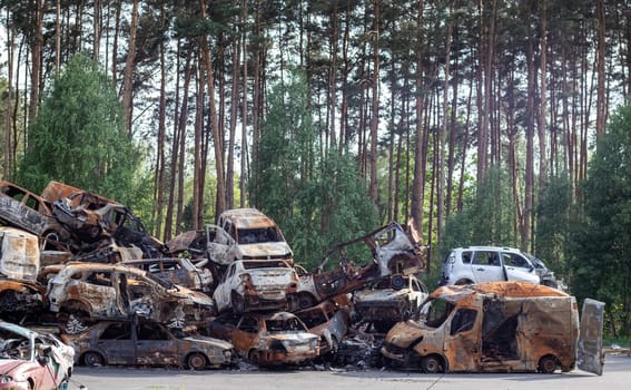 Rusty burnt cars destroyed by rocket explosions. War in Ukraine. Destroyed vehicles of civilians who were leaving were evacuated from the combat zone from Bucha and Irpin. Car graveyard